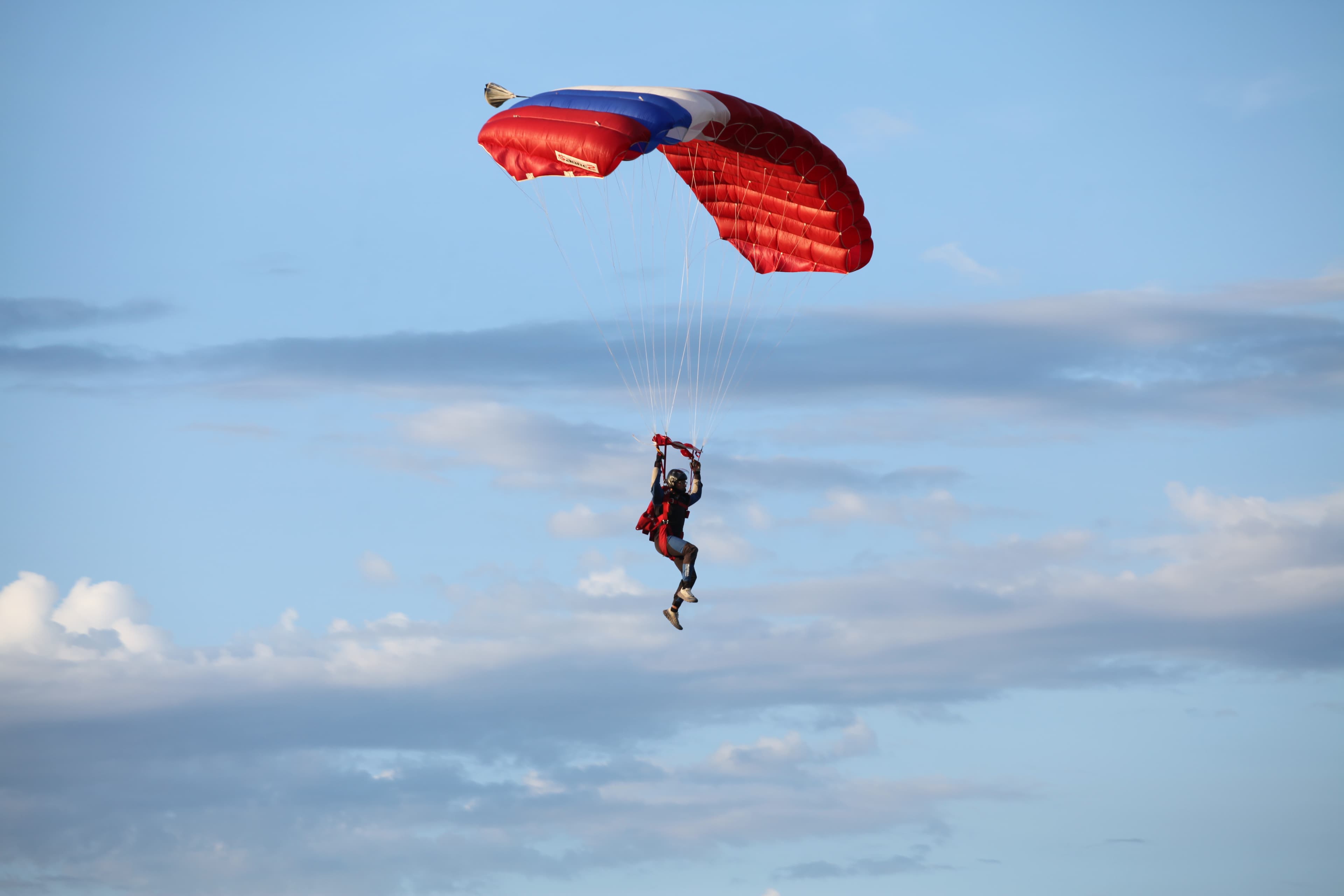 A skydiver under a red, white and blue canopy
